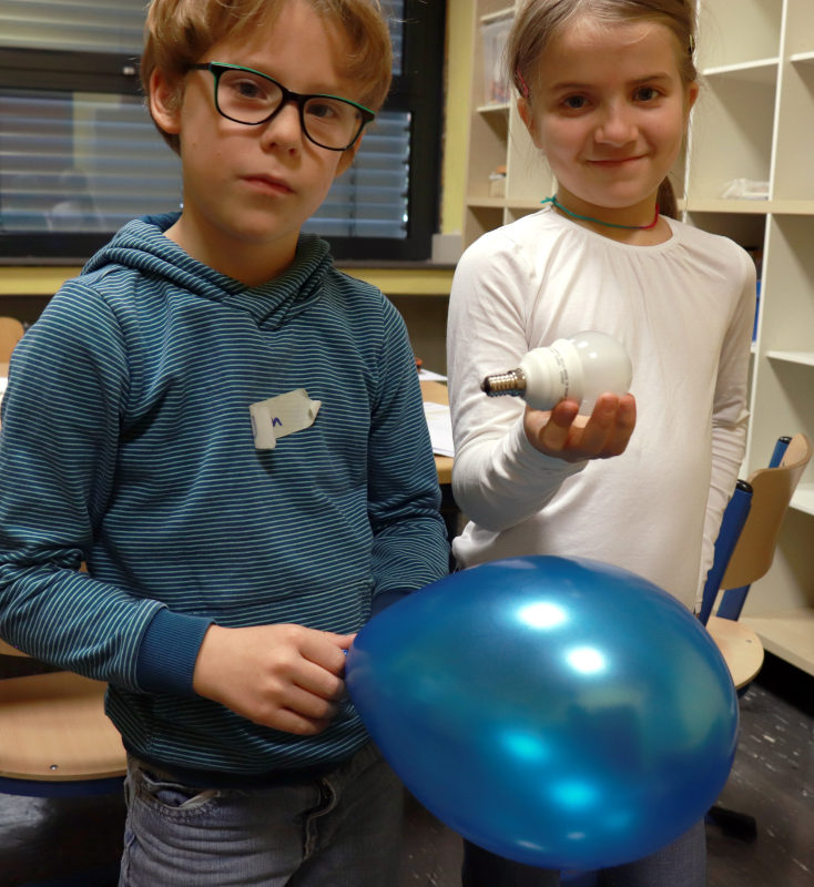 Zwei Kinder erzeugen einen kleinen Blitz mit einem Luftballon.